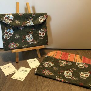 Pochette tissu motifs crânes, petites fleurs et oiseaux multicolores sur fond vert, intérieur à rayures multicolores orange, vert, jaune