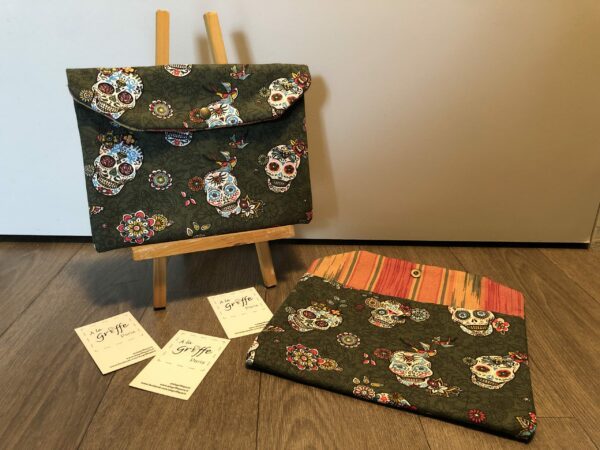 Pochette tissu motifs crânes, petites fleurs et oiseaux multicolores sur fond vert, intérieur à rayures multicolores orange, vert, jaune