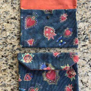 Pochette en coton enduit motif cœurs, roses, papillons, ailes, crânes et œils Multicolore sur fond vert. Tissu Intérieur Orange