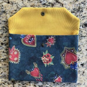 Pochette en coton enduit motif cœurs, roses, papillons, ailes, crânes et œils Multicolore sur fond vert. Tissu Intérieur jaune