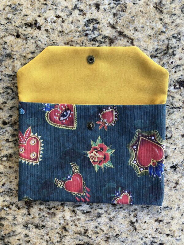 Pochette en coton enduit motif cœurs, roses, papillons, ailes, crânes et œils Multicolore sur fond vert. Tissu Intérieur jaune