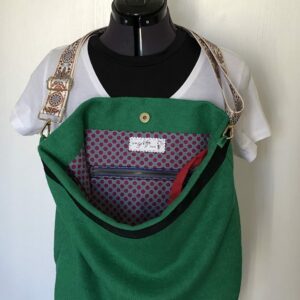 Sac en laine bouillie vert sapin à bandoulière réglable. Intérieur à motifs petits pois rouge grenat sur fond bleu clair
