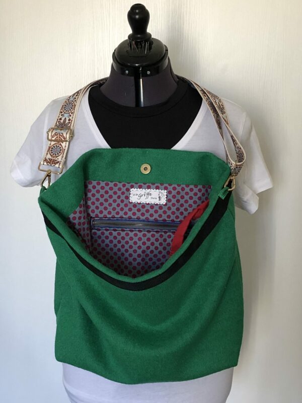 Sac en laine bouillie vert sapin à bandoulière réglable. Intérieur à motifs petits pois rouge grenat sur fond bleu clair
